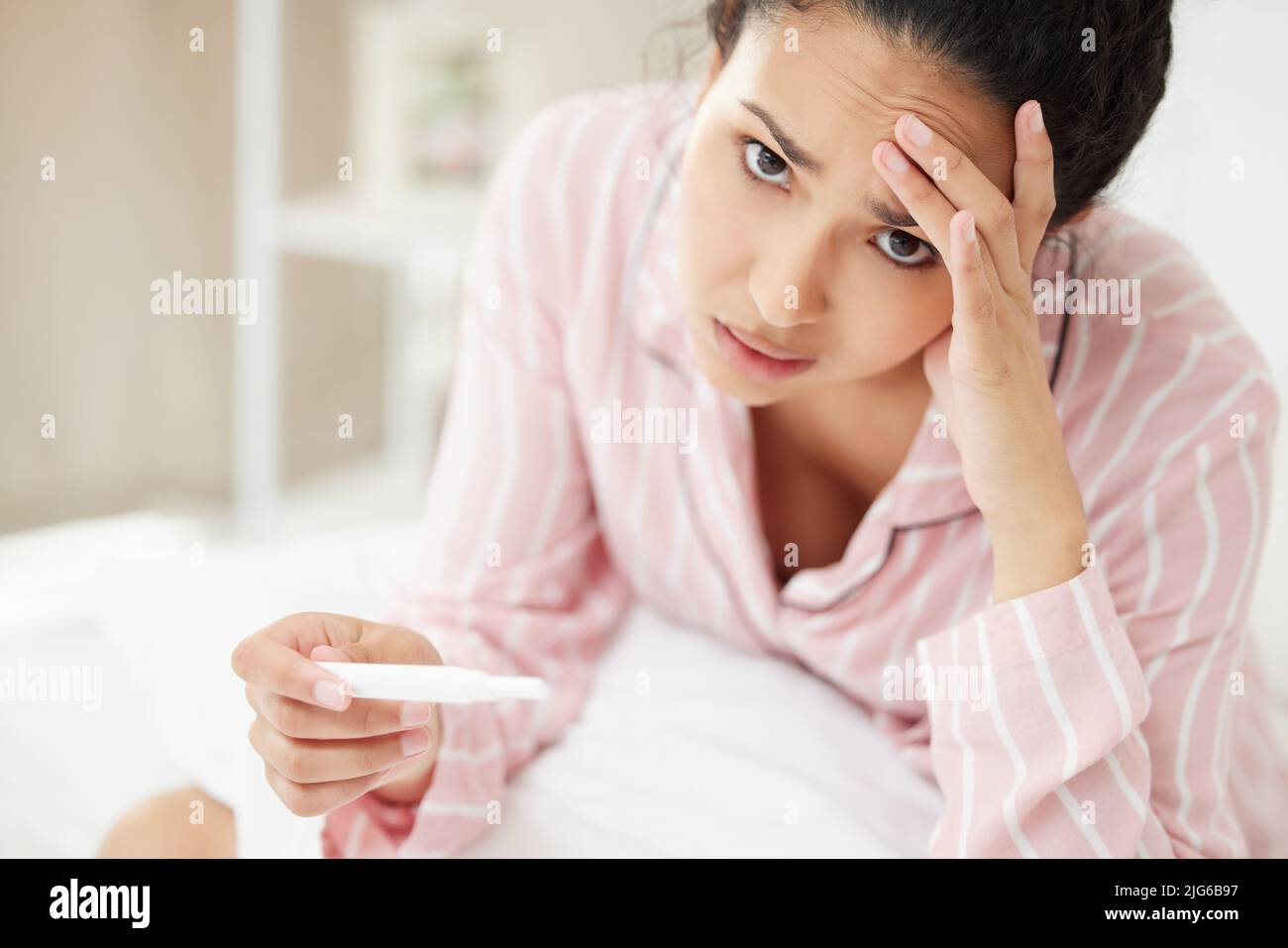 Je n'est pas prêt pour la maternité. Prise de vue d'une jeune femme qui a l'air stressée tout en tenant un test de grossesse. Banque D'Images