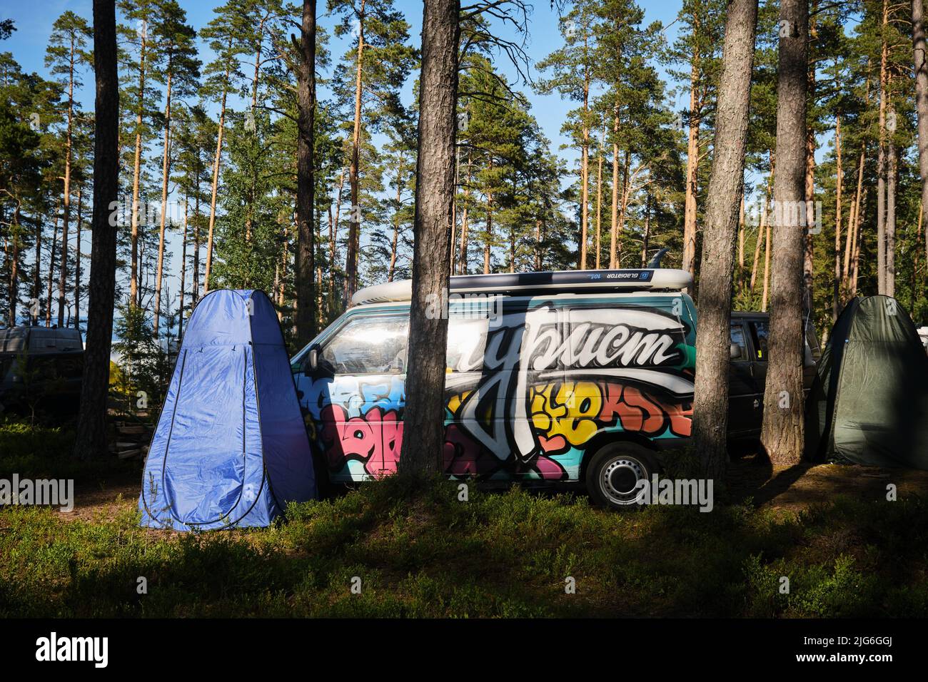 Leningrad Region, Russie - juin 2022. Camping dans la nature en forêt de conifères. Style Volkswagen transporter T4 décoré de graffiti avec sup surf Banque D'Images