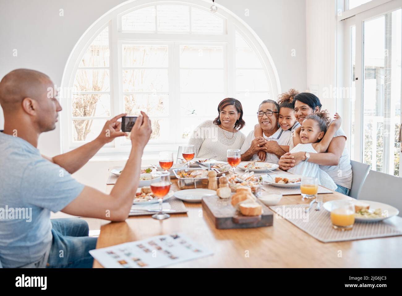 Je veux toujours me souvenir de ces moments. Photo d'un jeune père prenant des photos de sa famille pendant le déjeuner. Banque D'Images