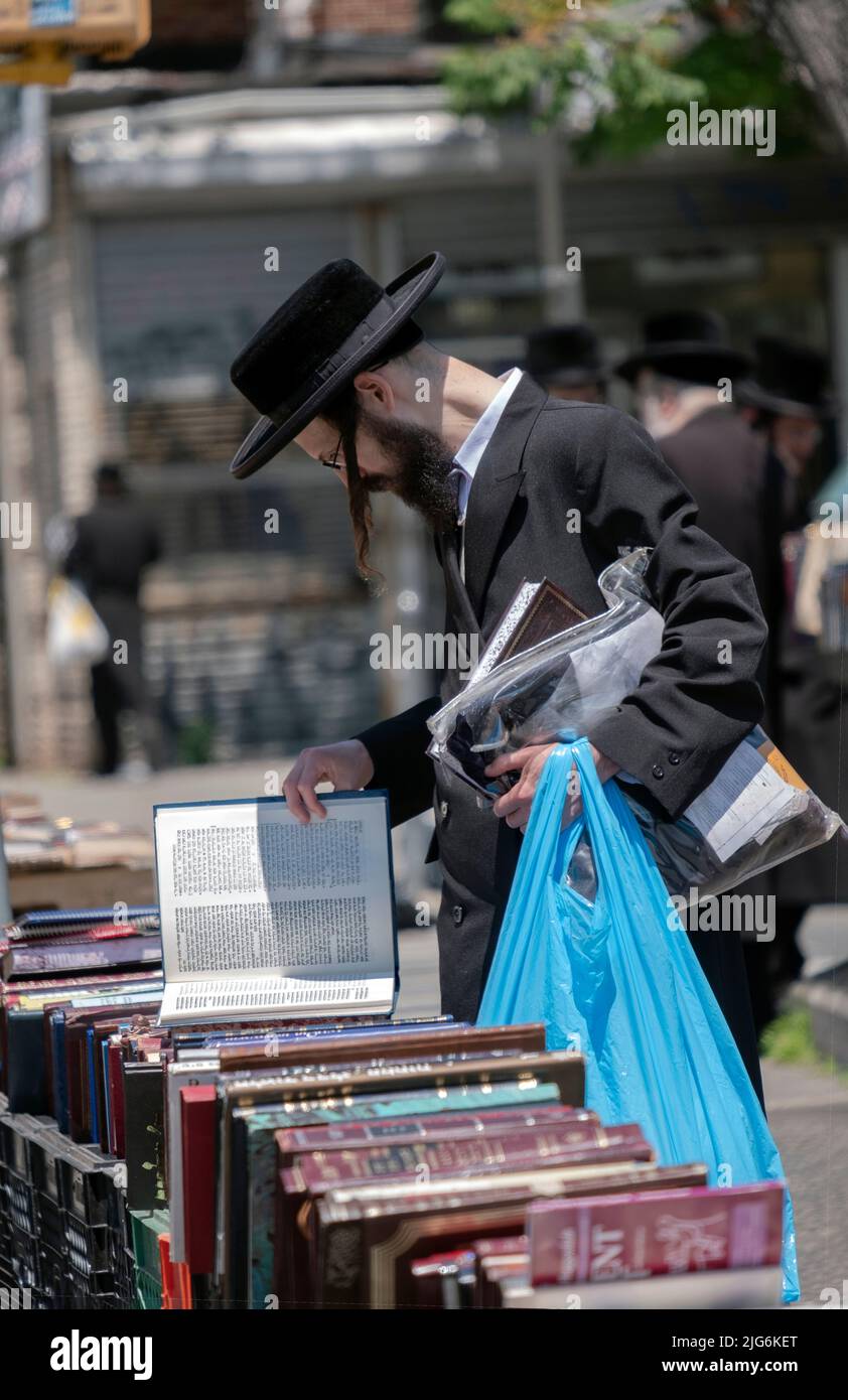 Un juif orthodoxe hassidique navigue à une vente extérieure de livres religieux. Sur Lee Avenue à Williamsburg Brooklyn, New York. Banque D'Images