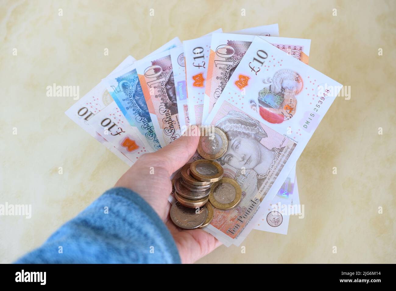 Billets et pièces de monnaie modernes britanniques en main. Banque D'Images