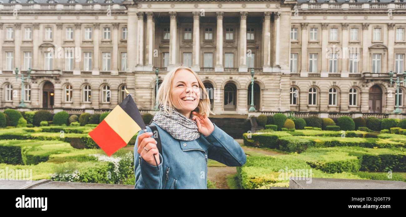 Une jeune femme avec le drapeau de la Belgique se tient sur le fond du Palais Royal de Bruxelles, regarde autour et sourit. Apprécier les visites touristiques et Banque D'Images