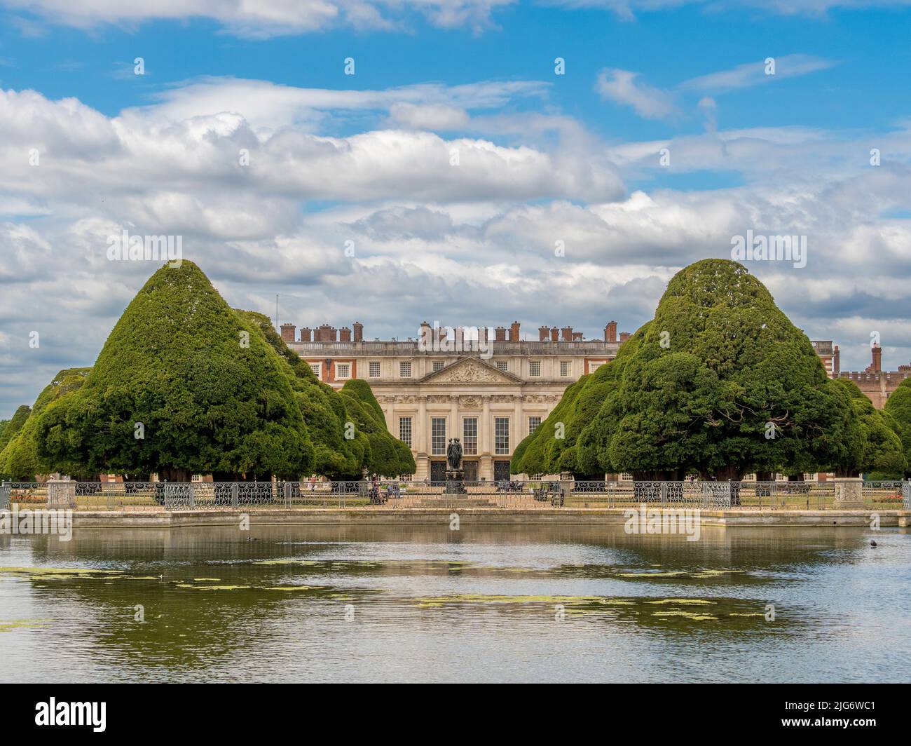 Face est du palais de Hampton court encadré par le jardin de la grande fontaine, les arbres sont plantés de longues eaux au premier plan. Londres. ROYAUME-UNI. Banque D'Images