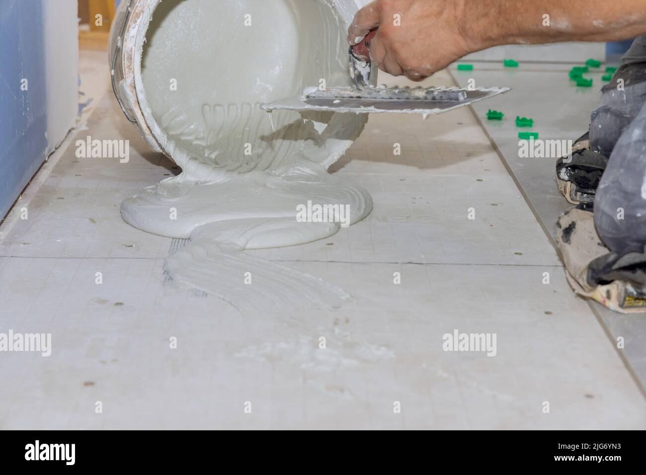En préparation de la pose des carreaux de sol, le mortier de truquage applique de l'adhésif sur un sol en béton Banque D'Images
