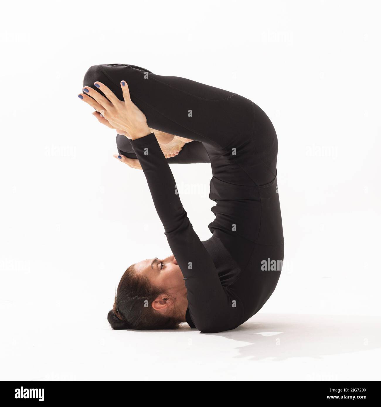 Femme pratiquant le yoga faisant un exercice Urdhva Padmasana, pose de lotus inversé, vue latérale sur fond blanc Banque D'Images