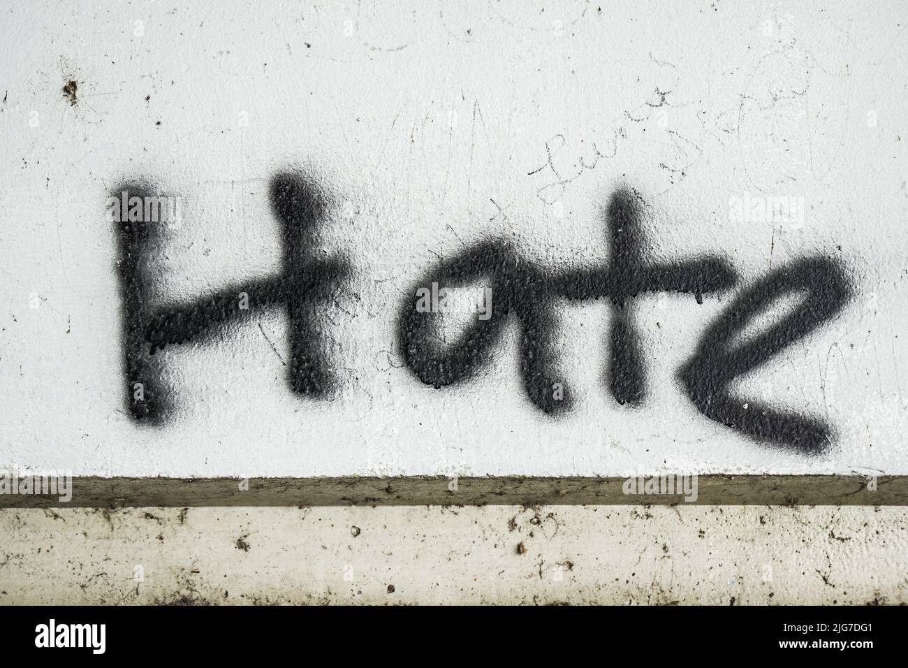 Haine écrite/peinte sur un mur en béton. Texture, message, citation, concept de déclaration. Banque D'Images