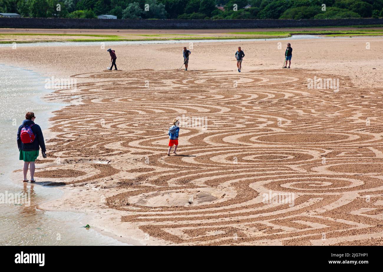 Belhaven Bay, East Lothian, Écosse, Royaume-Uni. 8th juillet 2022. Le dessin de sable au Festival européen d'art terrestre et aux Championnats de superposition de pierres, gérés par James Craig page, c'était la journée de la santé mentale et du bien-être, les artistes contributeurs sont : John Foreman du pays de Galles, Pedro Duran d'Espagne, Arron Tierney d'Écosse, Steve Winter d'Afrique du Sud. Le soleil et le vent fort à 38 km/h et les rafales potentielles de 66 km/h ont rendu la vie un peu difficile. Le festival d'une semaine se termine ce week-end. En photo : un jeune homme a vu l'œuvre d'un point de vue différent. Crédit : Arch White/alamy Live News Banque D'Images