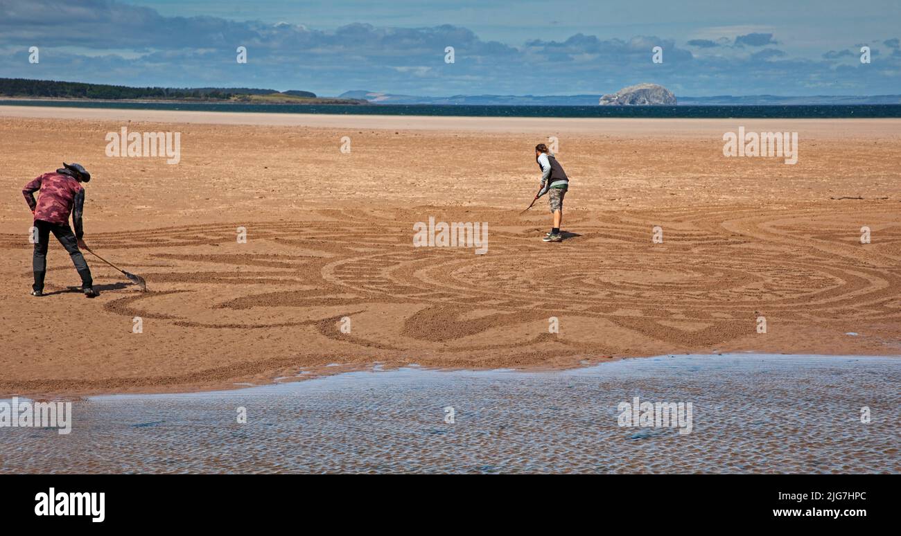 Belhaven Bay, East Lothian, Écosse, Royaume-Uni. 8th juillet 2022. Le dessin de sable au Festival européen d'art terrestre et aux Championnats de superposition de pierres, gérés par James Craig page, c'était la journée de la santé mentale et du bien-être, les artistes contributeurs sont : John Foreman du pays de Galles, Pedro Duran d'Espagne, Arron Tierney d'Écosse, Steve Winter d'Afrique du Sud. Le soleil et le vent fort à 38 km/h et les rafales potentielles de 66 km/h ont rendu la vie un peu difficile. Le festival d'une semaine se termine ce week-end. Crédit : Arch White/alamy Live News Banque D'Images