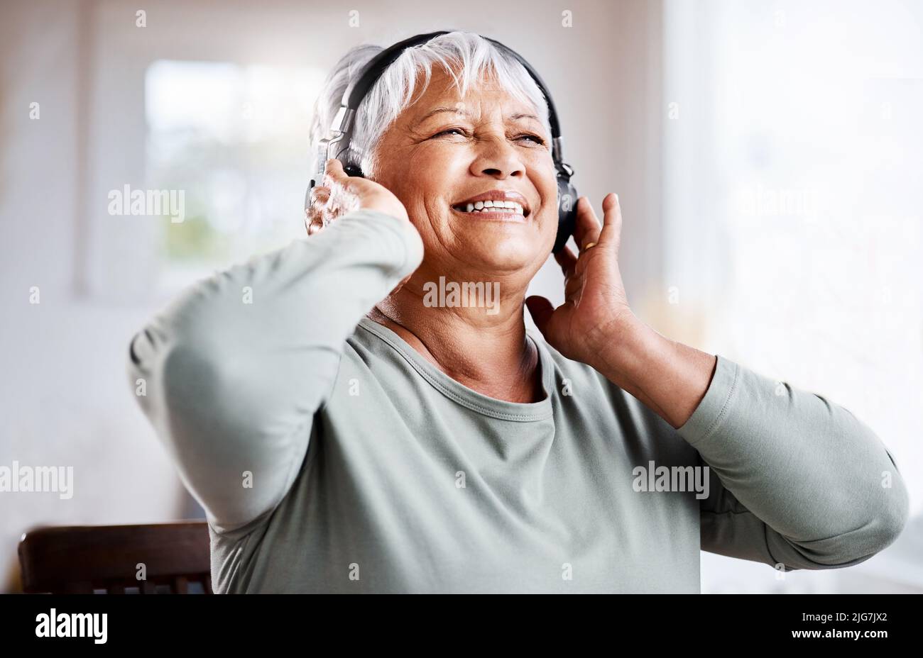 Il y a des façons de s'accrocher aux jeunes. Photo d'une belle femme âgée qui écoute de la musique tout en étant assise sur le canapé à la maison. Banque D'Images
