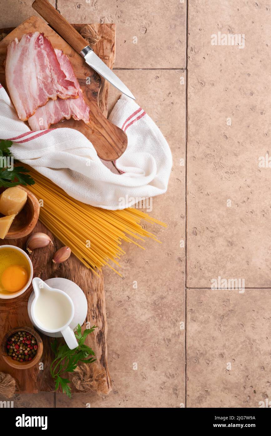 Ingrédients pour pâtes Carbonara. Pâtes italiennes Traidtional Carbonara Ingrédients bacon, spaghetti, parmesan et jaune d'œuf, ail. Table ancienne en carrelage beige Banque D'Images