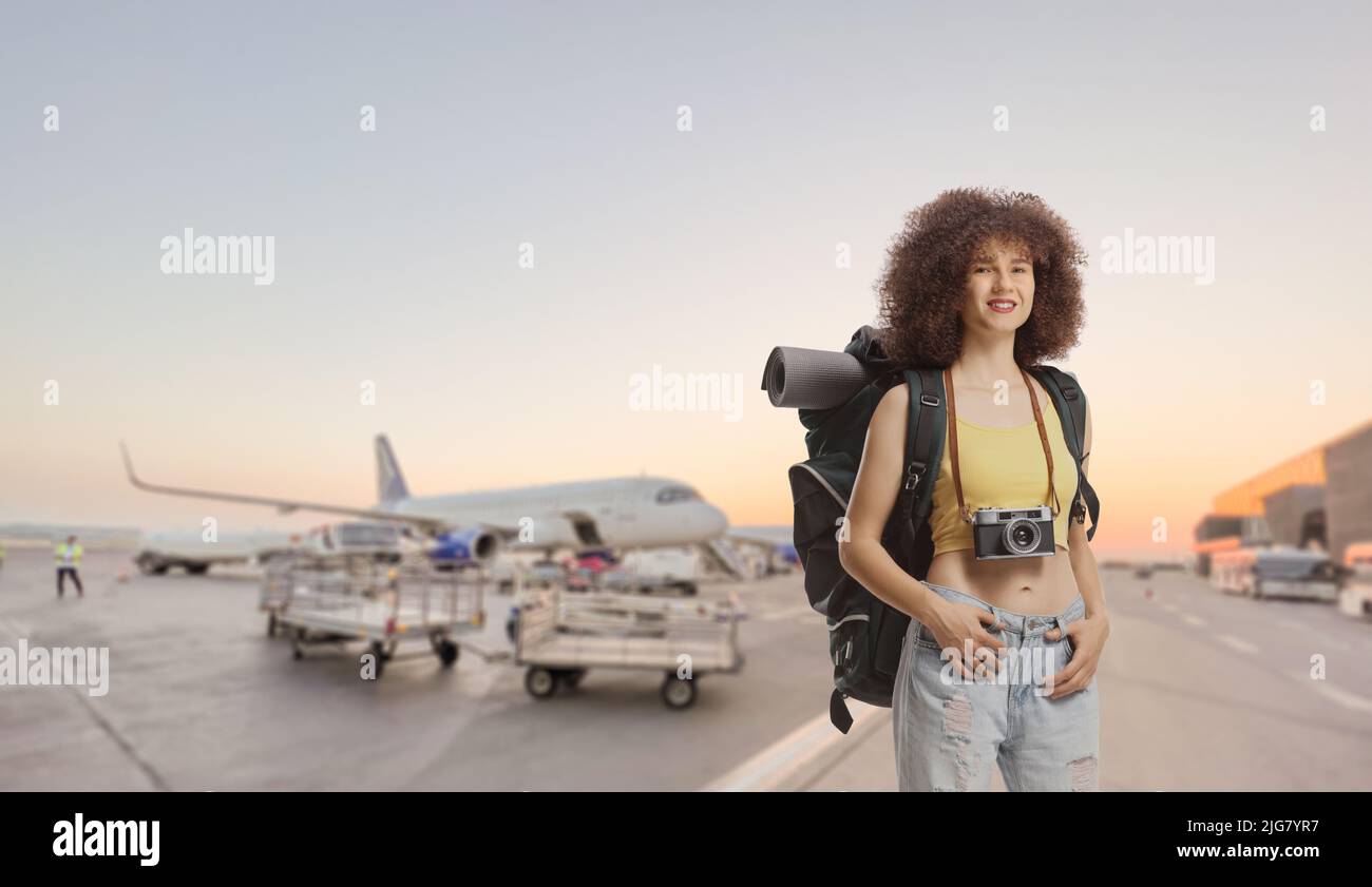 Jeune femme voyageur avec un sac à dos debout sur un tablier d'aéroport Banque D'Images