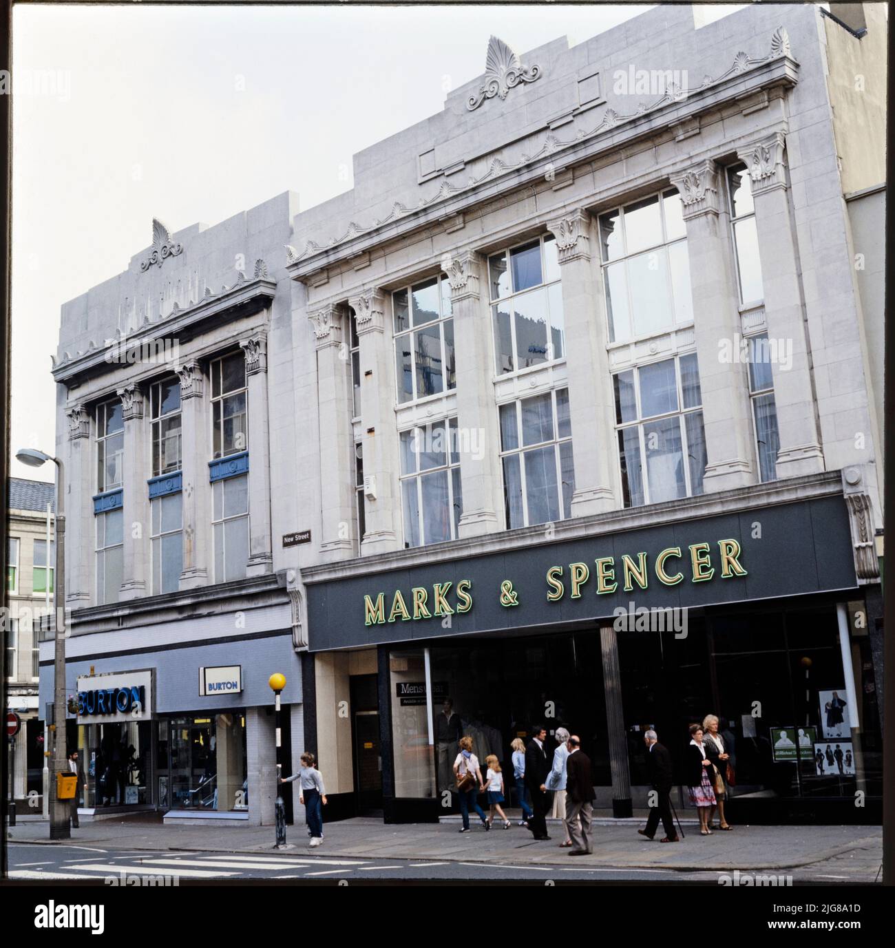 Marks and Spencer, 17-23 New Street, Huddersfield, Kirklees, 1970s-1990s. Les élévations avant des magasins Burton et Marks and Spencer de conception similaire au 17-23 New Street. Marks and Spencer a déménagé d'un site existant à Huddersfield vers l'ancien site de Burton, au 19-23 New Street, en 1934. Burton a fait l'acquisition du site d'angle, situé au 17 New Street, et a construit un petit magasin d'un design presque identique. Le magasin Burton avait fermé ses portes en 2008 et les locaux étaient occupés par Vision Express. The Marks and Spencer a fermé ses portes en 2019. Banque D'Images