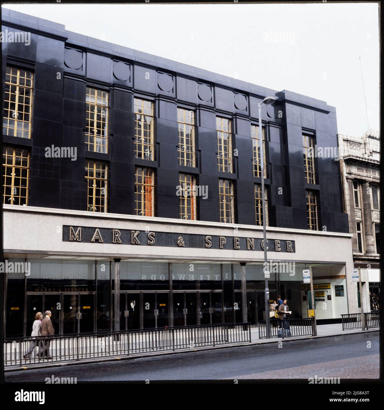 Marks and Spencer, 47-49 Briggate, Leeds, 1970s-1990s. L'élévation avant du magasin Marks and Spencer au 47-49 Briggate, montrant la façade en granit poli foncé et les barres de vitrage dorées dans les fenêtres de l'étage supérieur. Marks and Spencer a ouvert ses portes à Leeds au 76 Briggate en 1909. Le magasin n° 47-49 Briggate a ouvert ses portes en 1951. C'est l'un des quelques exemples de magasins Marks and Spencer aux façades en granit, un autre étant le Panthéon, Londres. Banque D'Images