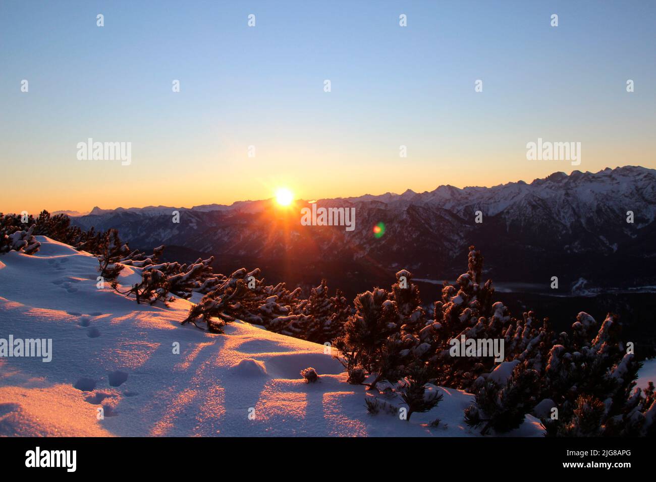 Lever du soleil pendant la randonnée d'hiver à travers la forêt de montagne à Simetsberg. Feu arrière, chemin, Allemagne, Bavière, Walchensee, Einsiedl Banque D'Images