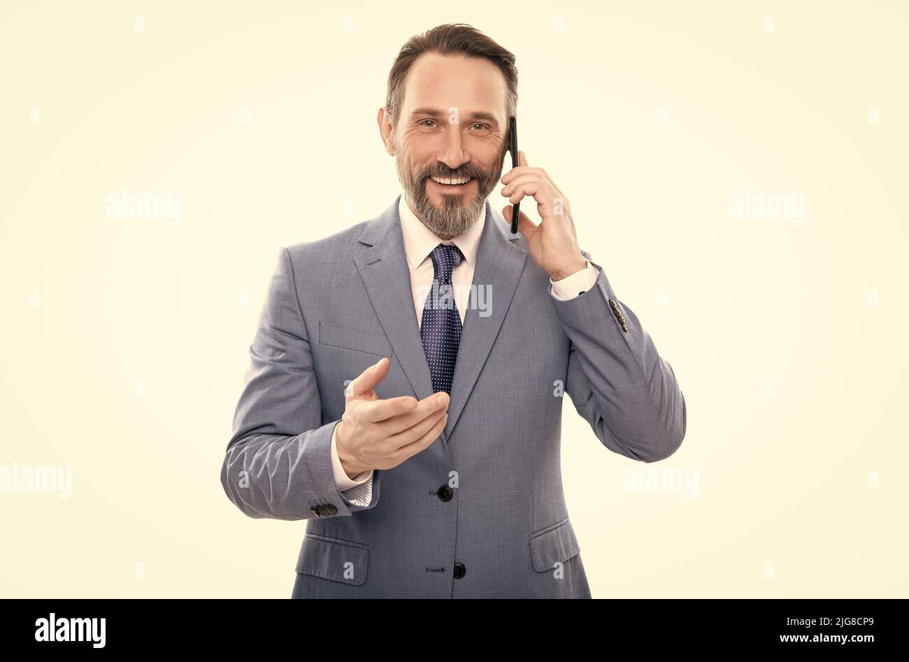 souriant entrepreneur grizzled en costume parlant sur smartphone isolé sur blanc, négociations d'affaires Banque D'Images