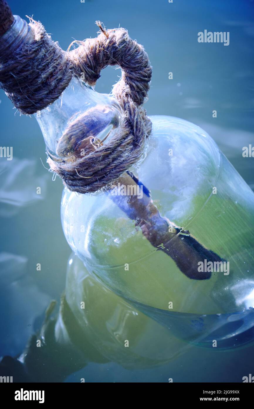 Bouteille flottant sur l'eau avec une lettre laminée à l'intérieur.appel de message pour l'aide Banque D'Images
