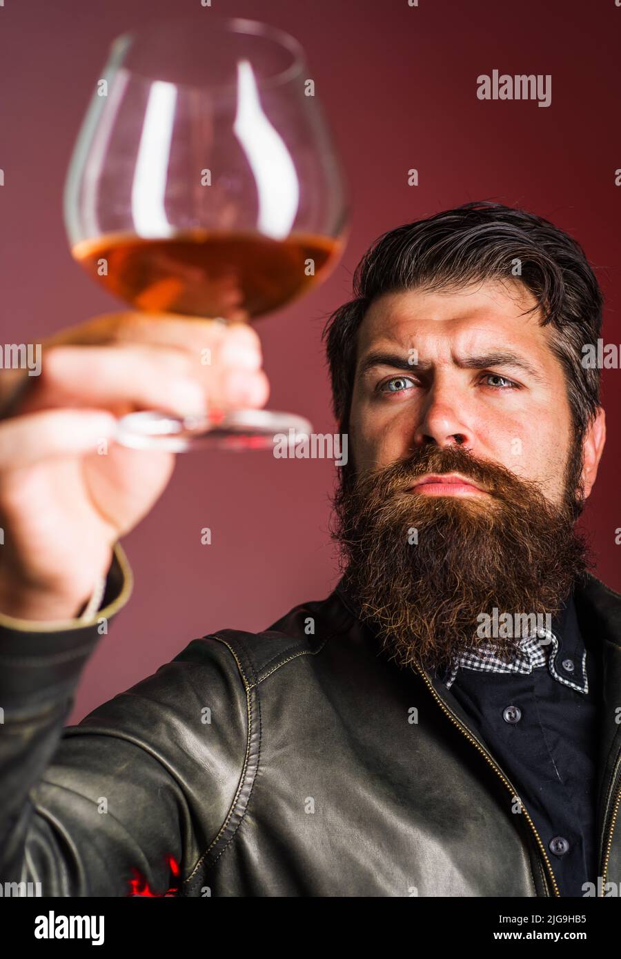 Homme barbu avec un verre de whisky ou de brandy. Boisson alcoolisée. Dégustation, dégustation. Fête, vacances. Banque D'Images