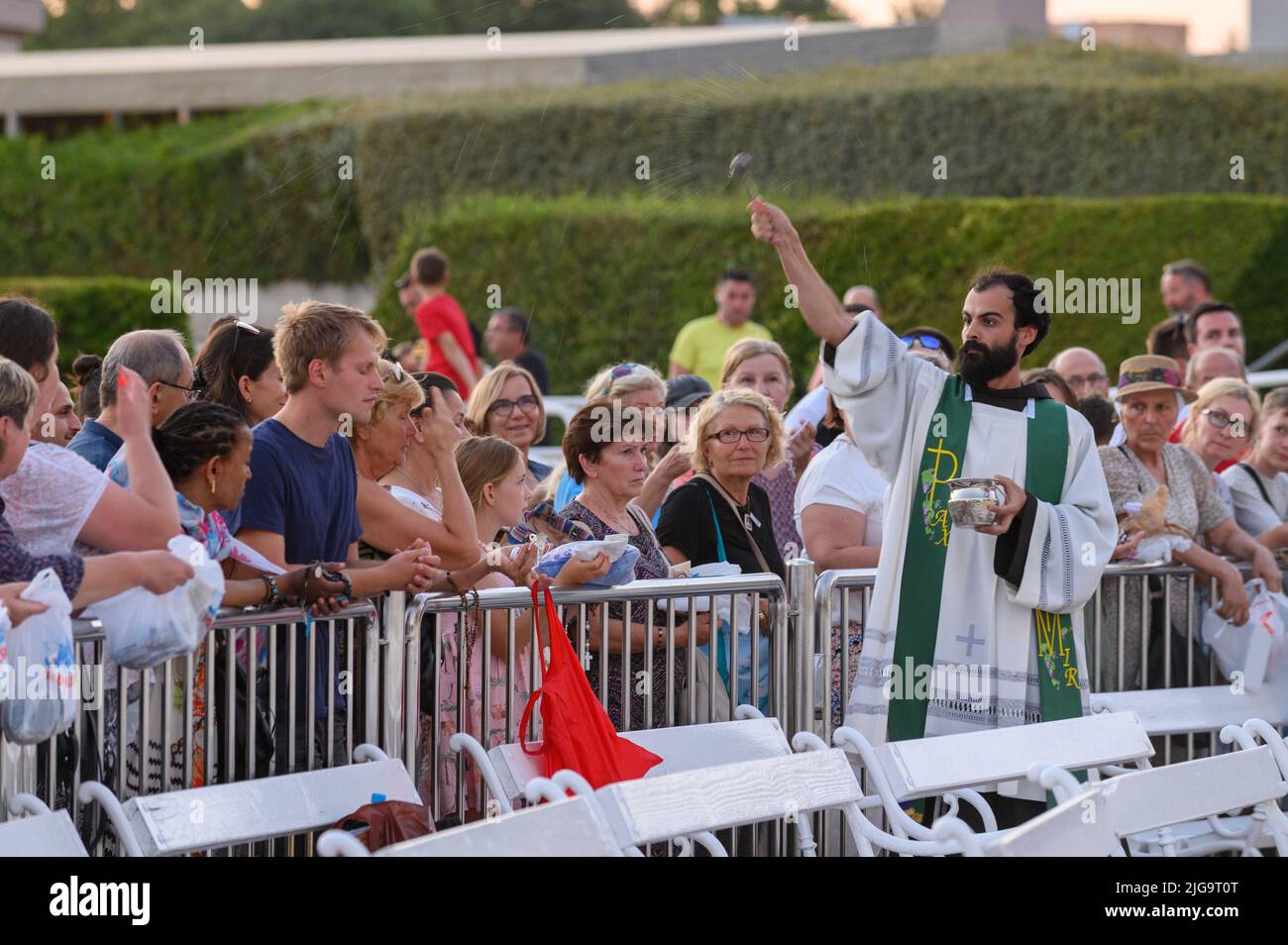 Un prêtre bénit les articles religieux des fidèles après la Messe du soir à Medjugorje. Banque D'Images