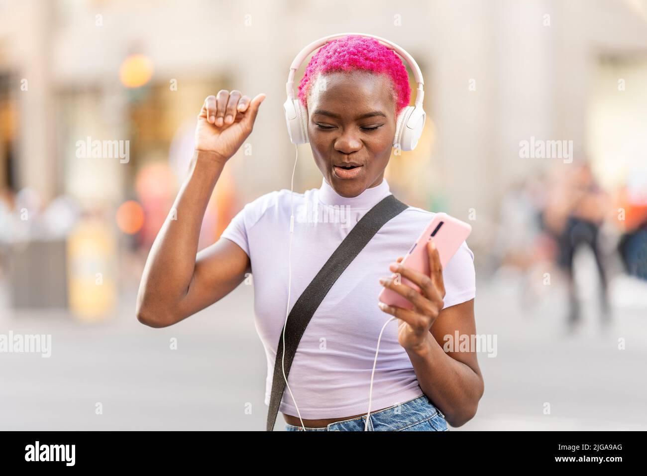 Femme africaine dansant tout en écoutant de la musique avec des écouteurs à l'extérieur Banque D'Images