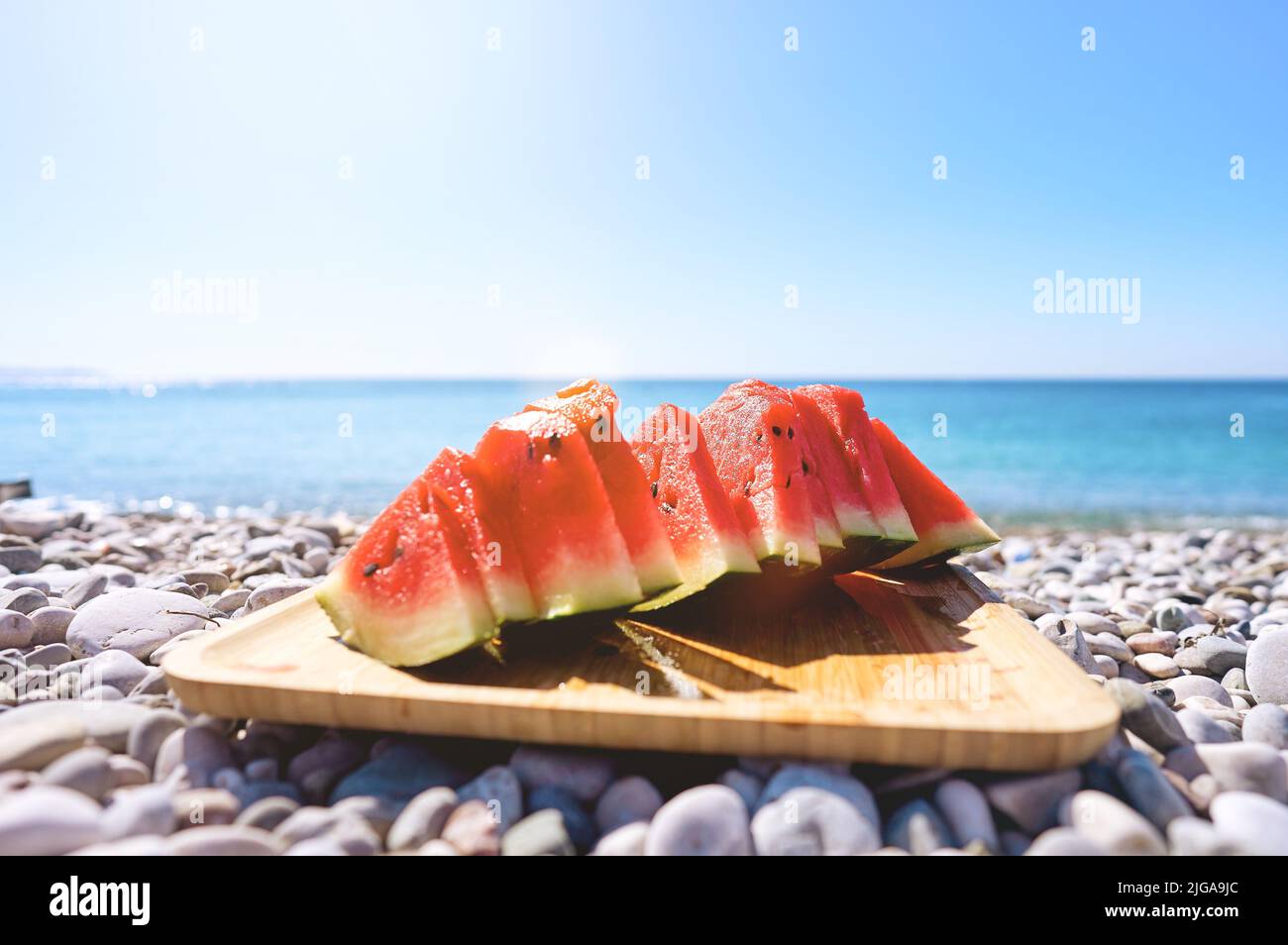 Tranches de pastèque juteuses sur l'assiette. En arrière-plan la mer et la plage. Pastèque rouge, fruits frais. Heure d'été. Banque D'Images