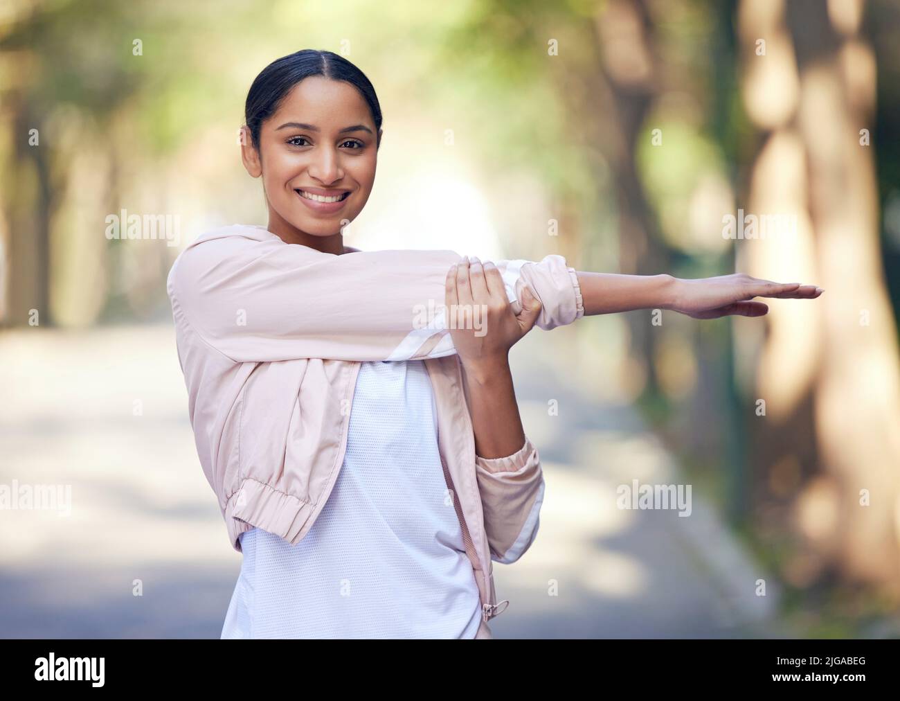 J'aime toujours mes courses du matin en solo. Portrait d'une jeune femme sportive qui étire les bras tout en faisant de l'exercice à l'extérieur. Banque D'Images