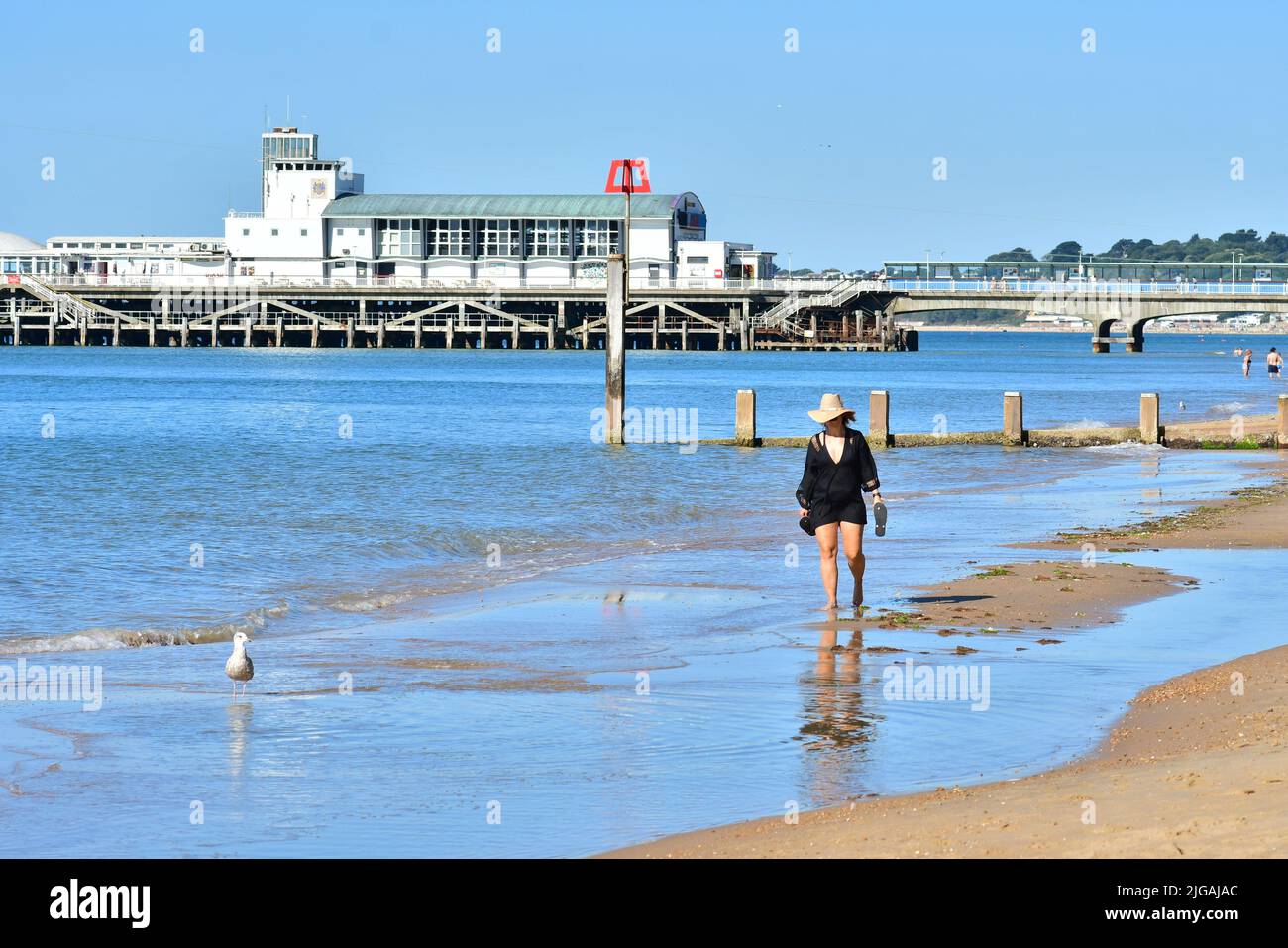 Bournemouth, Dorset, Angleterre, Royaume-Uni, 9th juillet 2022, Météo. Onde de chaleur. Les gens arrivent à la plage avant 9 heures le samedi matin. Les températures atteindront la température élevée de 20s par après-midi sous le soleil de mur à mur. Femme marchant sur la plage. Crédit : Paul Biggins/Alamy Live News Banque D'Images