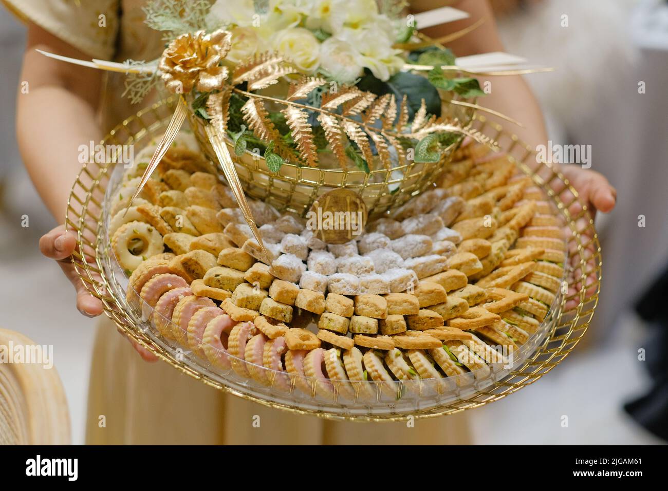 Plateau doré rond de pâtisseries et de bonbons arabes traditionnels transportés par un serveur comme apéritif lors d'un mariage émirati à Dubaï, Émirats arabes Unis. Banque D'Images