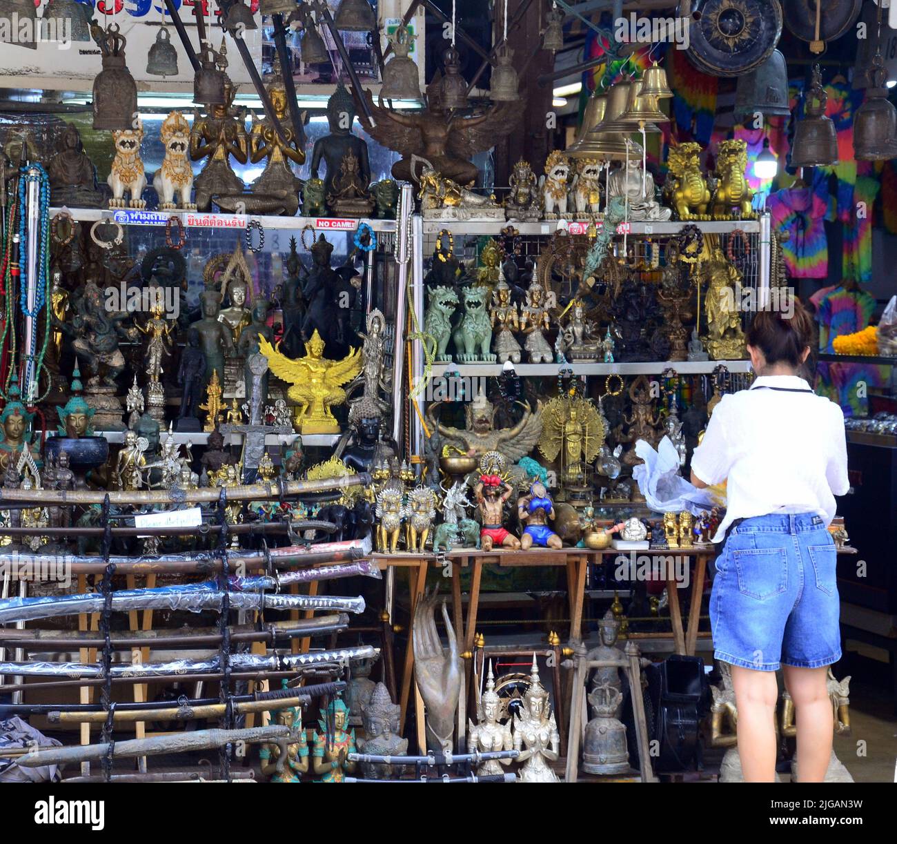 Un membre du personnel ajuste les antiquités pour les vendre dans un stand au marché du week-end de Chatuchak, Bangkok, Thaïlande, Asie. Le marché est le plus grand marché de Thaïlande. Banque D'Images