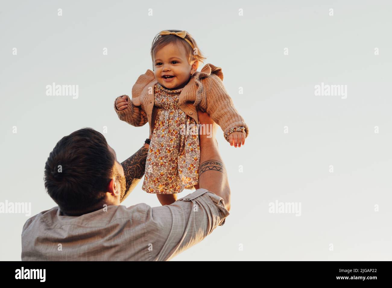 Daddy lever sa fille de bébé dans les bras sur le ciel arrière-plan au coucher du soleil, concept de la Journée des pères heureux Banque D'Images