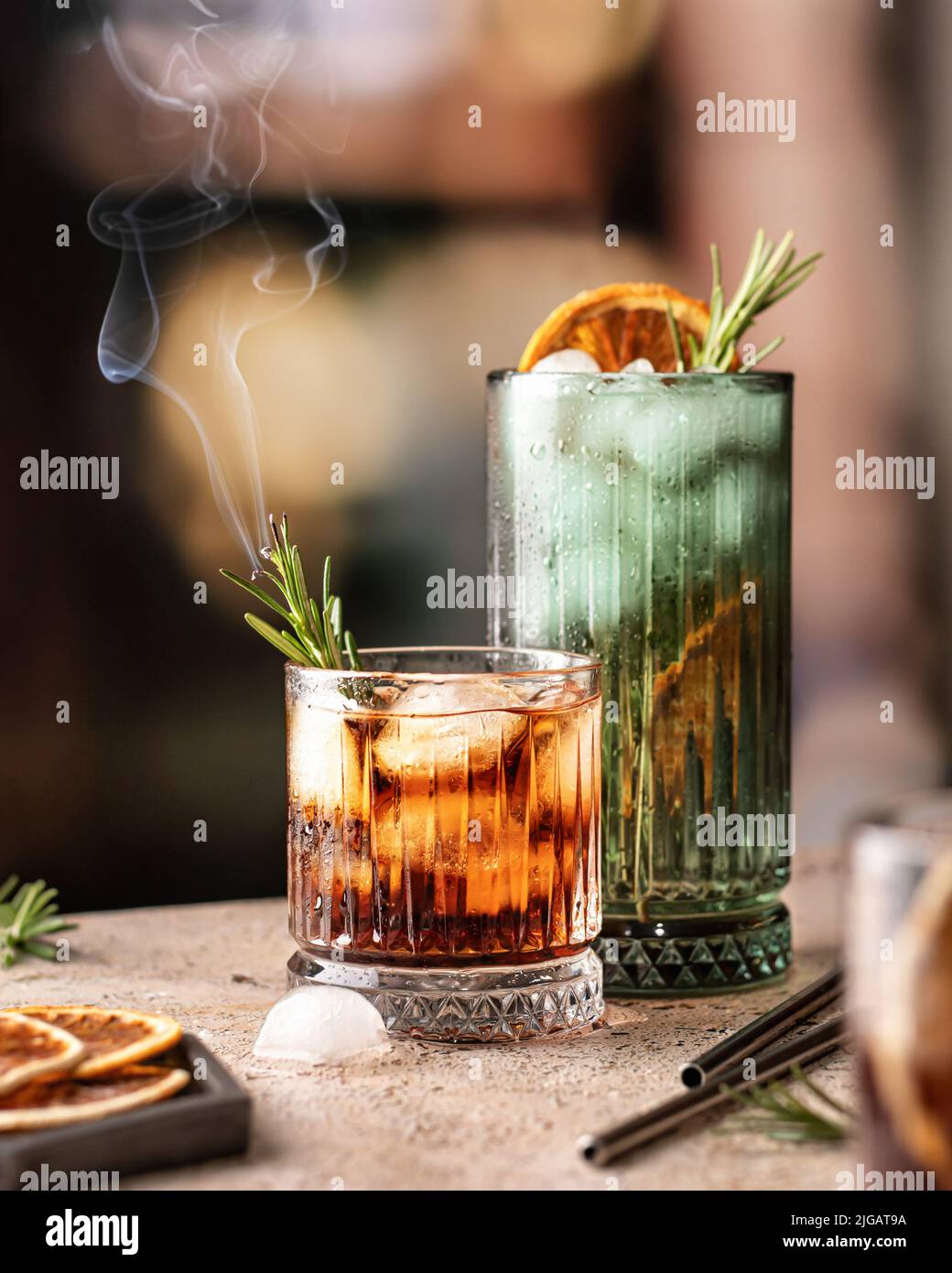 Cocktails au bar. Whisky-cola, cuba libre cocktails glacés avec du romarin à la vapeur et des pailles métalliques derrière. Orientation verticale Banque D'Images