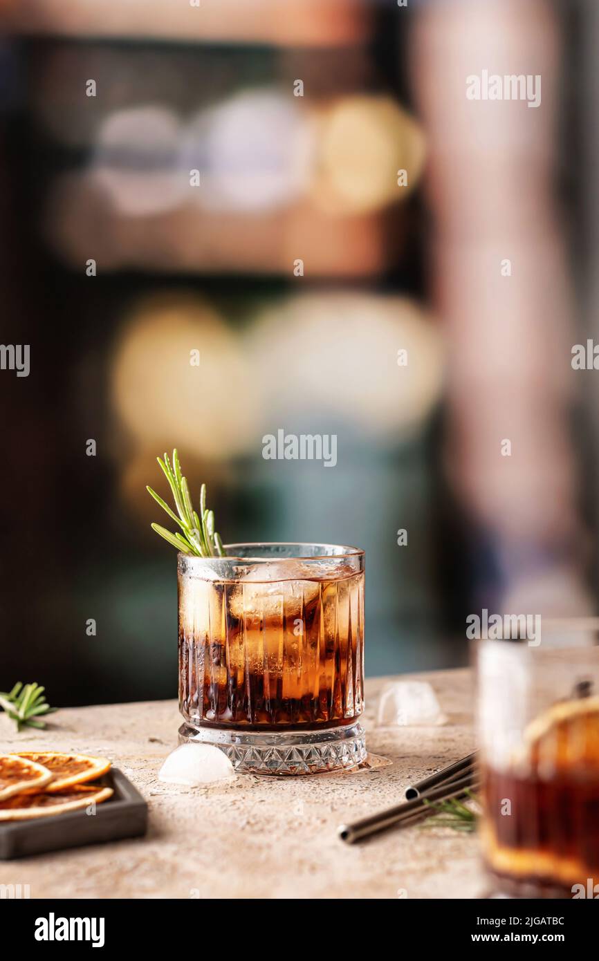 Cocktails glacés au whisky-cola ou au cuba libre avec pailles de romarin et de métal au bar. Orientation verticale Banque D'Images