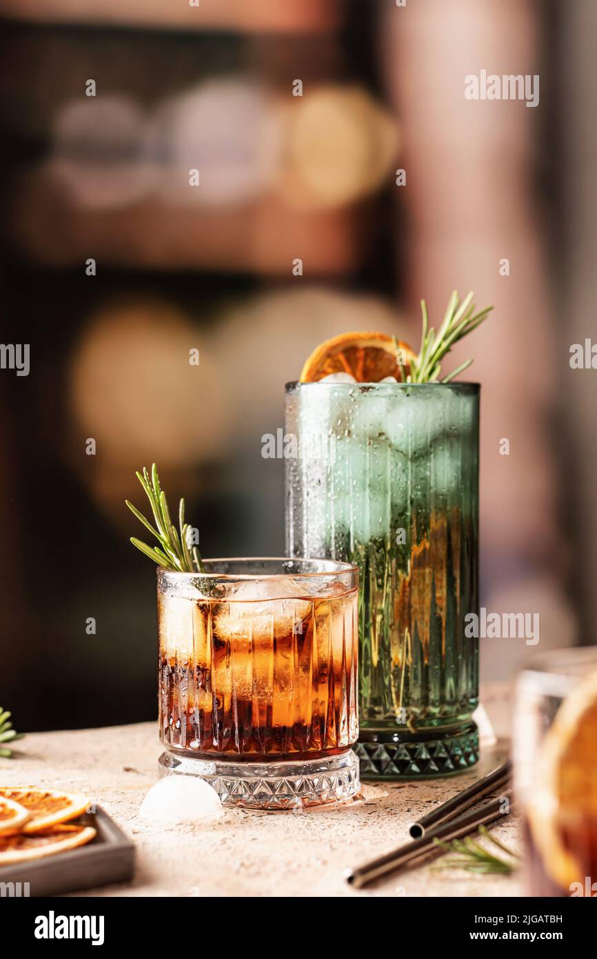 Cocktails au bar. Whisky-cola, cuba libre cocktails glacés avec romarin et tranches d'orange séchées avec pailles métalliques. Espace de texte. Vertical ou Banque D'Images