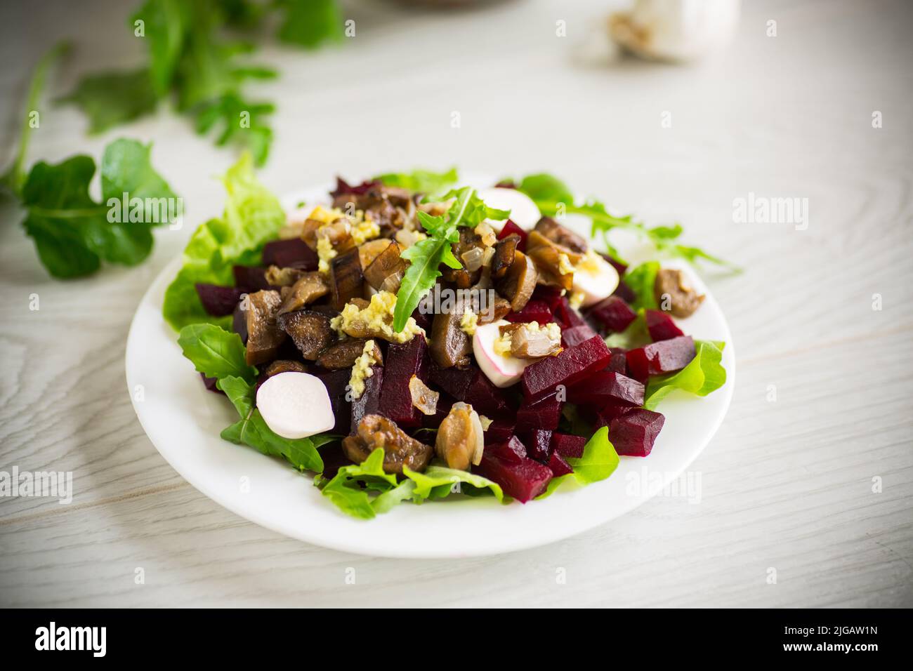 Salade avec des betteraves cuites, des aubergines frites, des herbes et des arugula dans une assiette, sur une table en bois. Banque D'Images