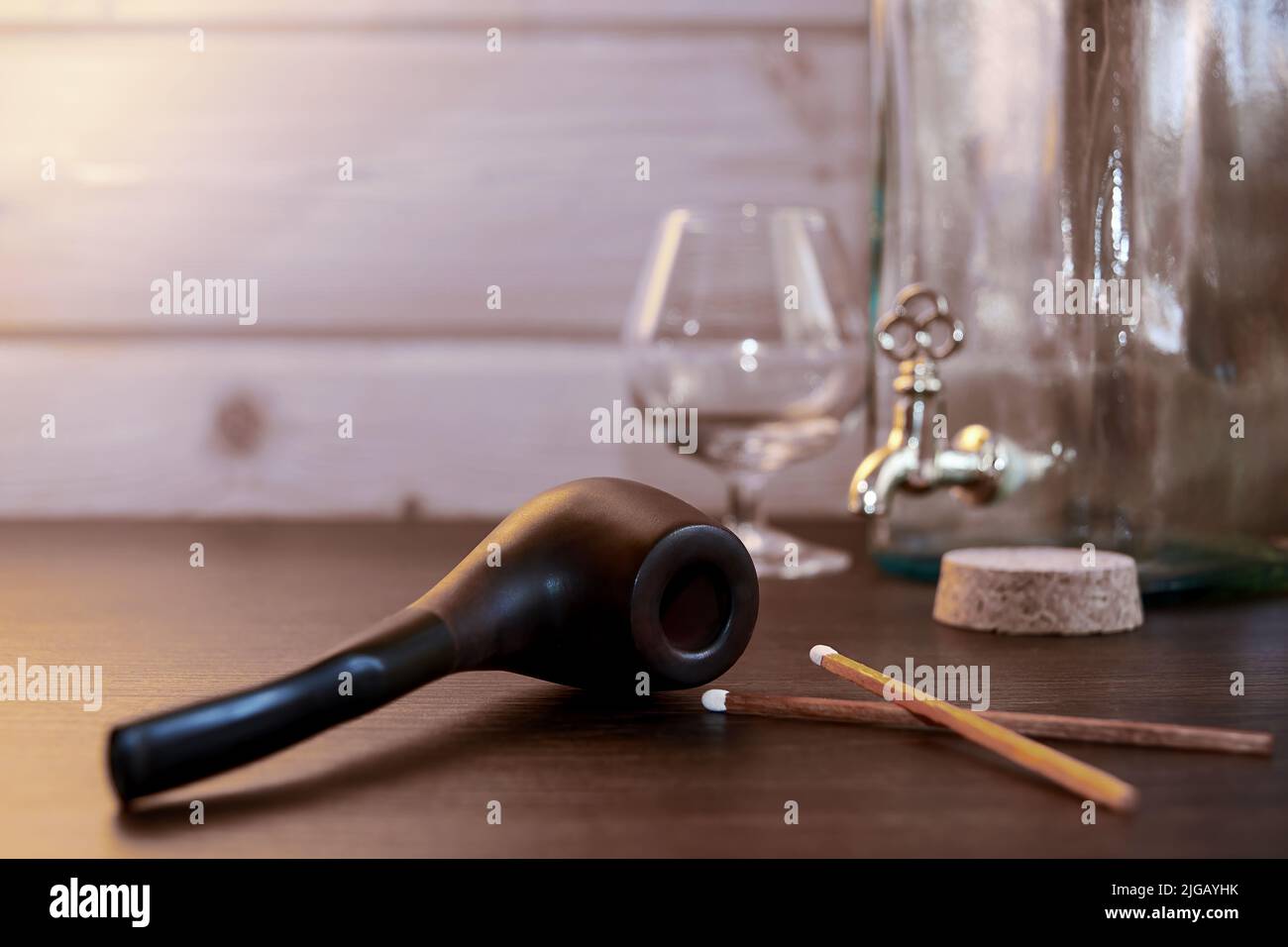 Table en bois dans la maison avec pipe à fumer, tabac, allumettes et brandy. Activités de loisirs en soirée et détente Banque D'Images