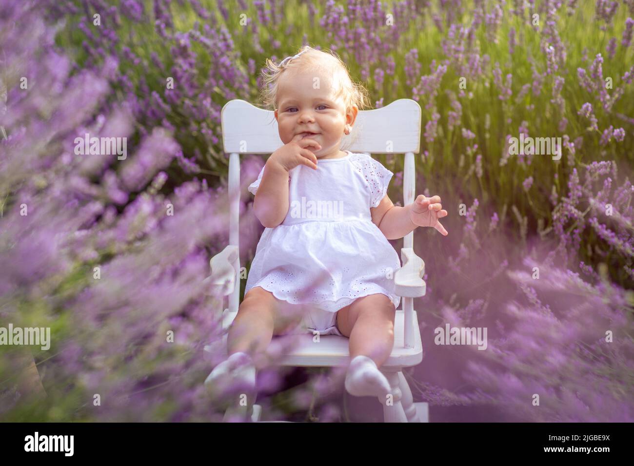 Petite fille souriante assise à la prairie de lavande. Banque D'Images