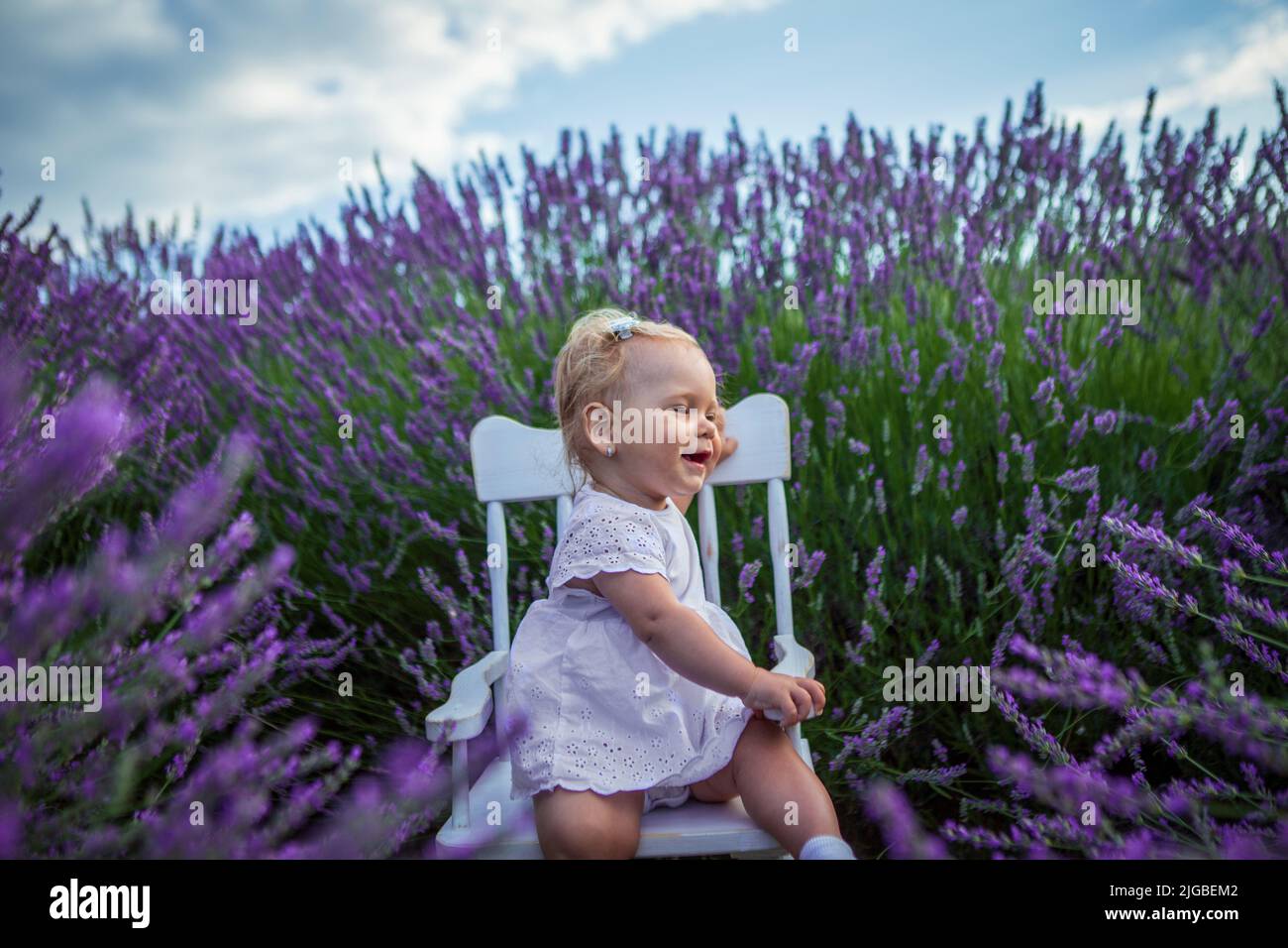 Bonne petite fille mignonne dans un champ de lavande au coucher du soleil. Banque D'Images