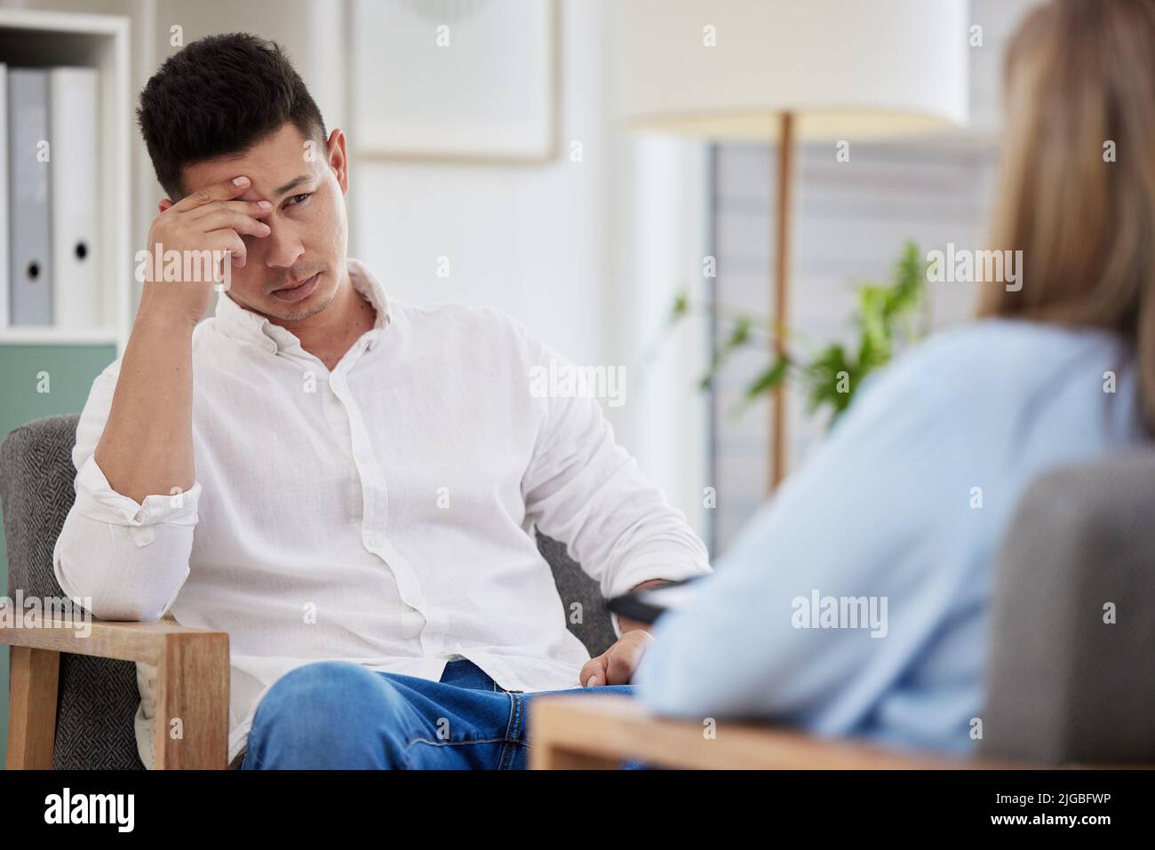 Il y a tellement de choses qui se passent. Un beau jeune homme assis dans la clinique avec son thérapeute et se sentant stressé. Banque D'Images