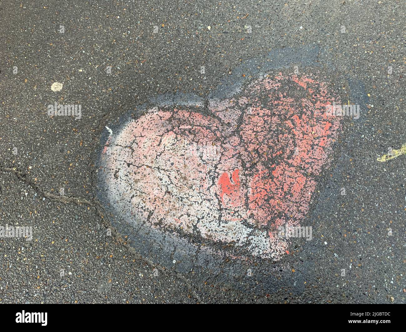 Coeur rose dessinant sur l'asphalte Banque D'Images