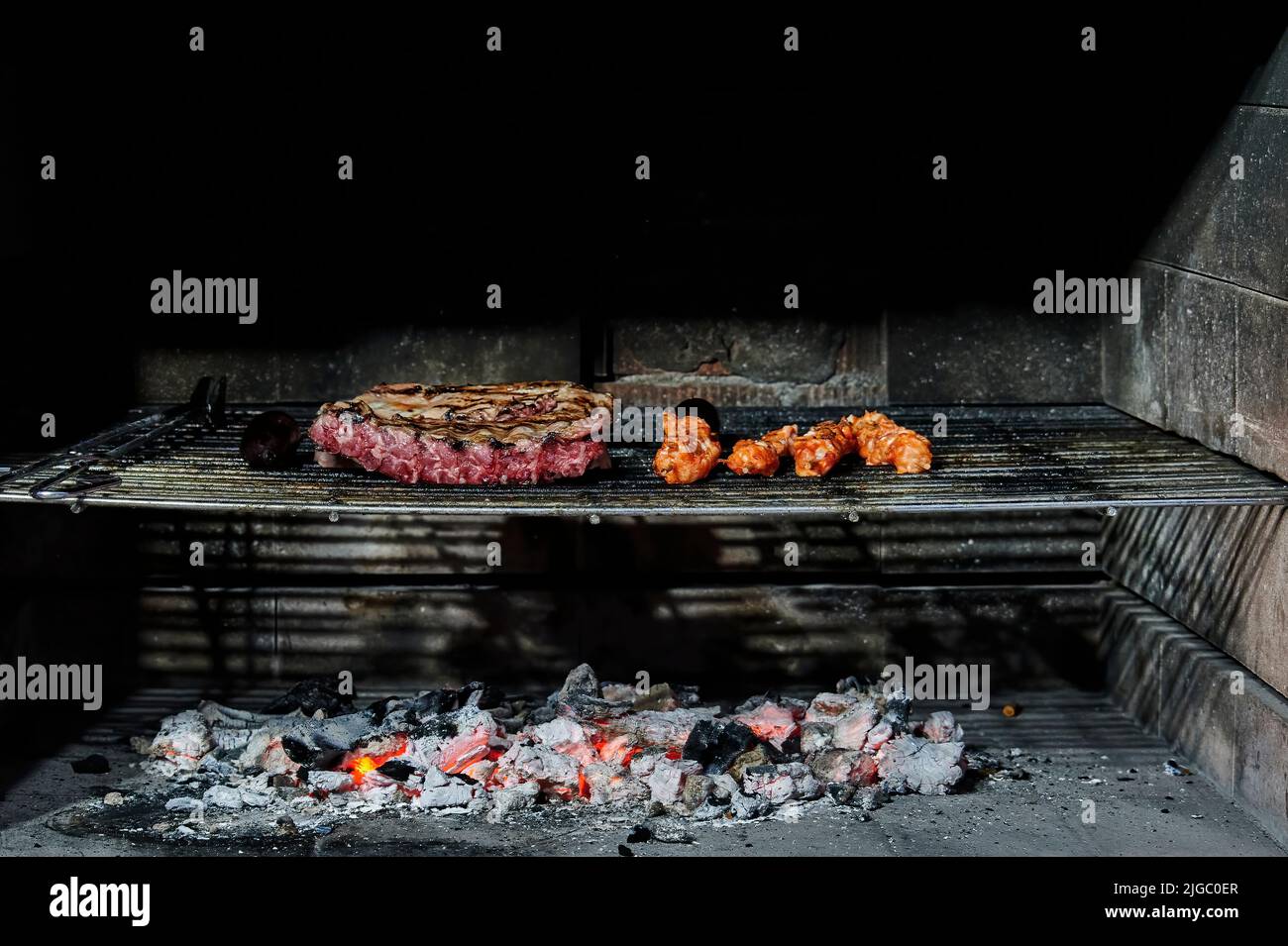 Côtes de porc et brochettes de poulet marinées cuisant au charbon de bois sur une grille de barbecue Banque D'Images
