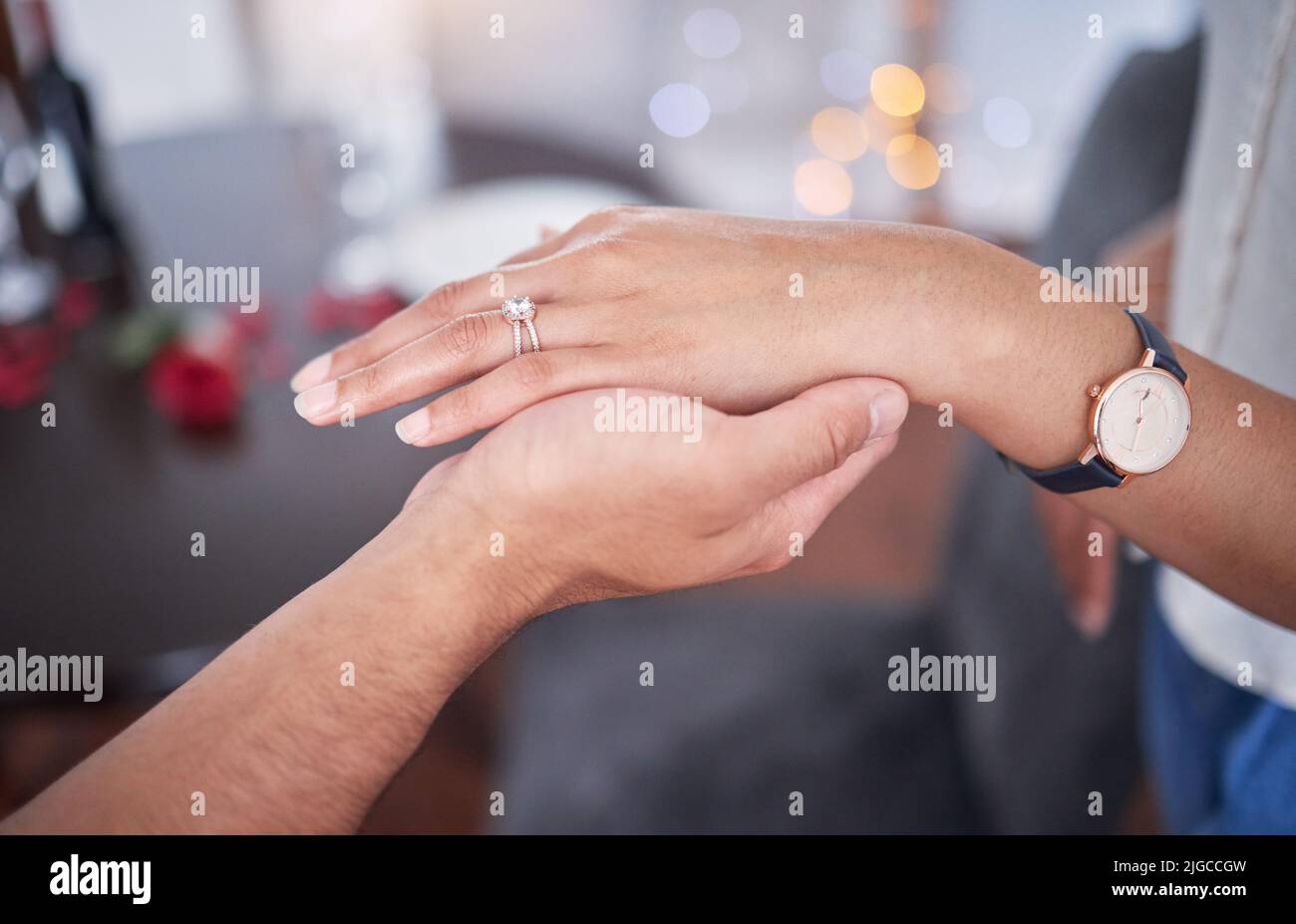Notre toujours commence aujourd'hui. Un homme méconnaissable mettant une bague sur le doigt de ses amies à la maison. Banque D'Images