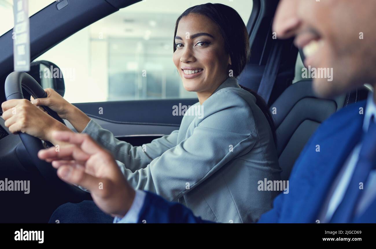 Il sera difficile de dire non... Portrait court d'une jeune femme attrayante assise dans une nouvelle voiture tout en parlant à un beau vendeur de voiture mâle Banque D'Images