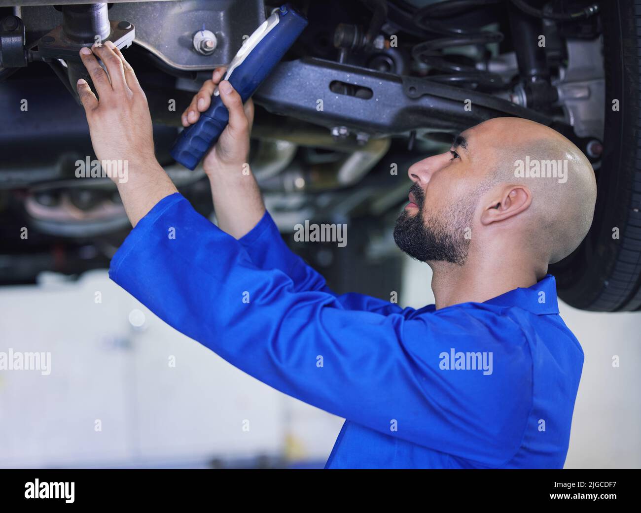 Briller un peu de lumière sur cette situation. Un beau jeune homme mécanicien travaillant sur le moteur d'une voiture pendant un service. Banque D'Images