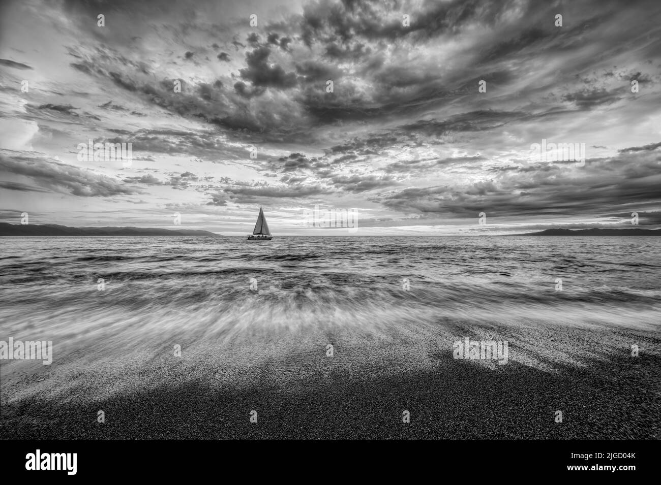 Les nuages détaillés sont au-dessus de la tête lorsQu'Un petit bateau se déplace le long de l'horizon océanique noir et blanc Banque D'Images