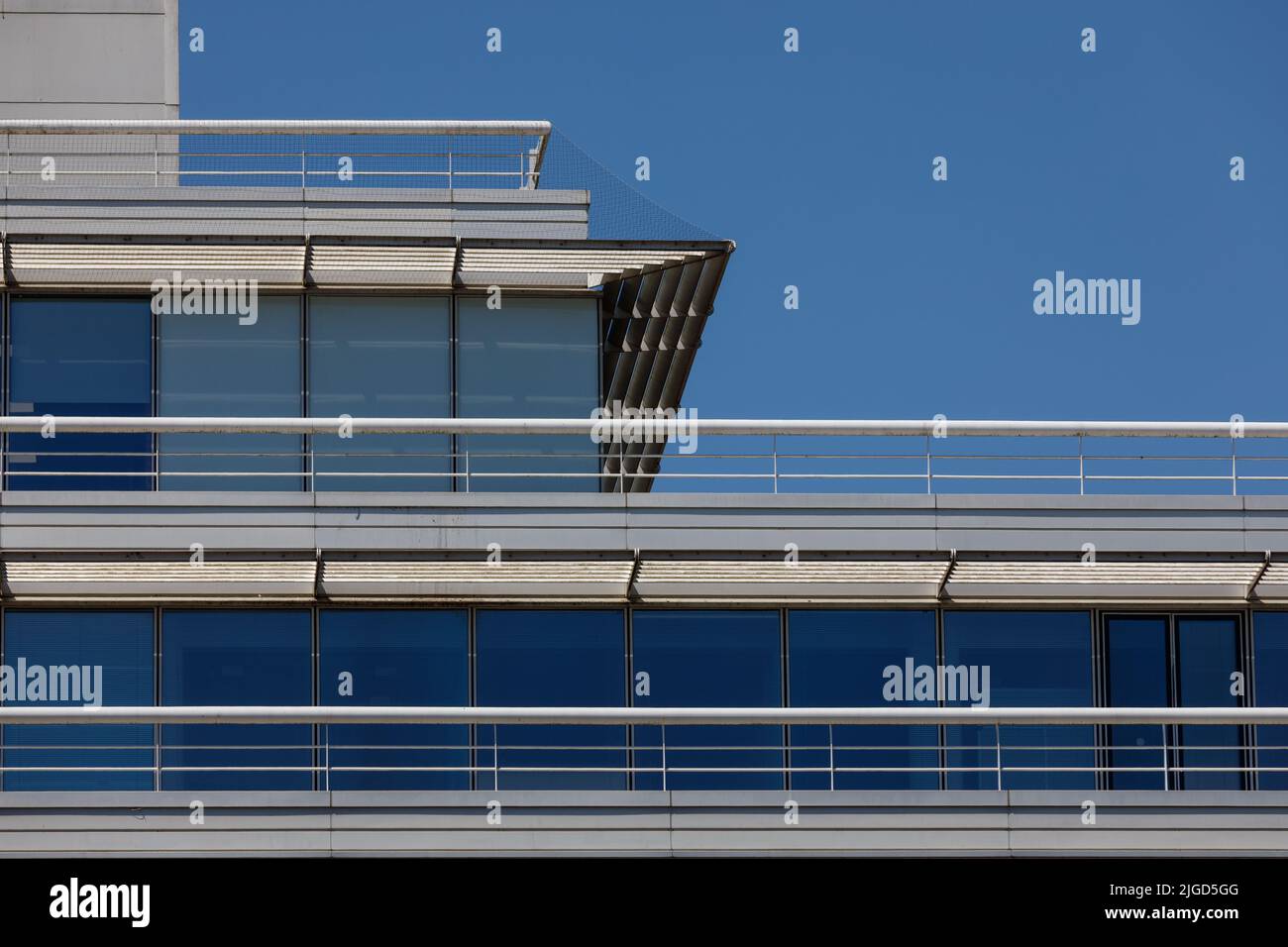 Détail du toit et du dernier étage d'un bâtiment moderne avec des lattes et des garde-corps de pare-soleil horizontaux et des cadres de fenêtre verticaux contre bleu clair sk Banque D'Images