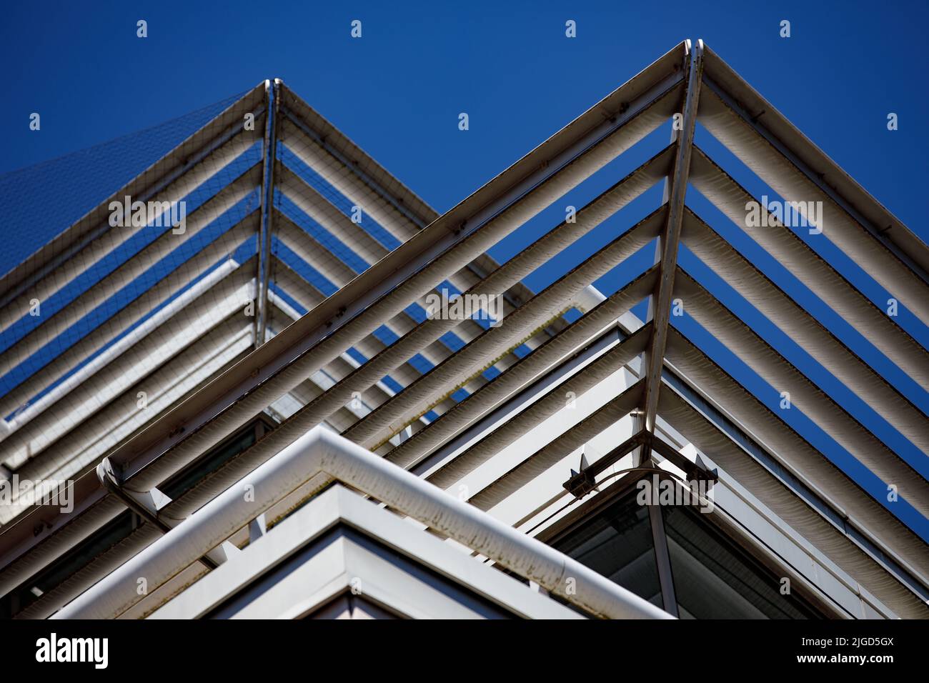 Vue abstraite des panneaux d'ombrage solaire créant des lignes triangulaires sur le côté extérieur d'un immeuble de bureaux Banque D'Images