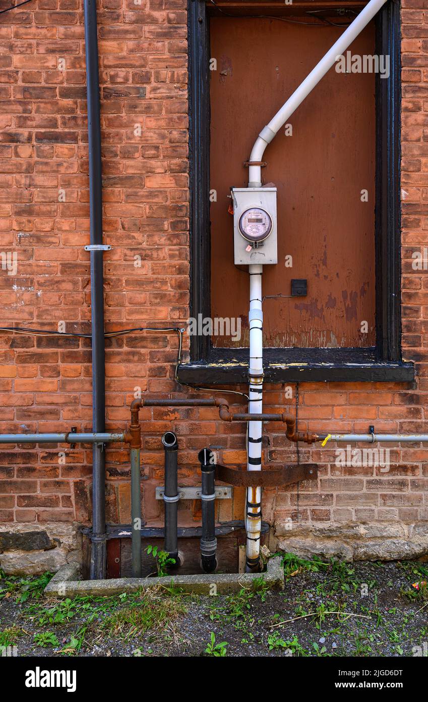 tuyaux d'échappement et compteur d'électricité sur le vieux mur en brique rouge Banque D'Images