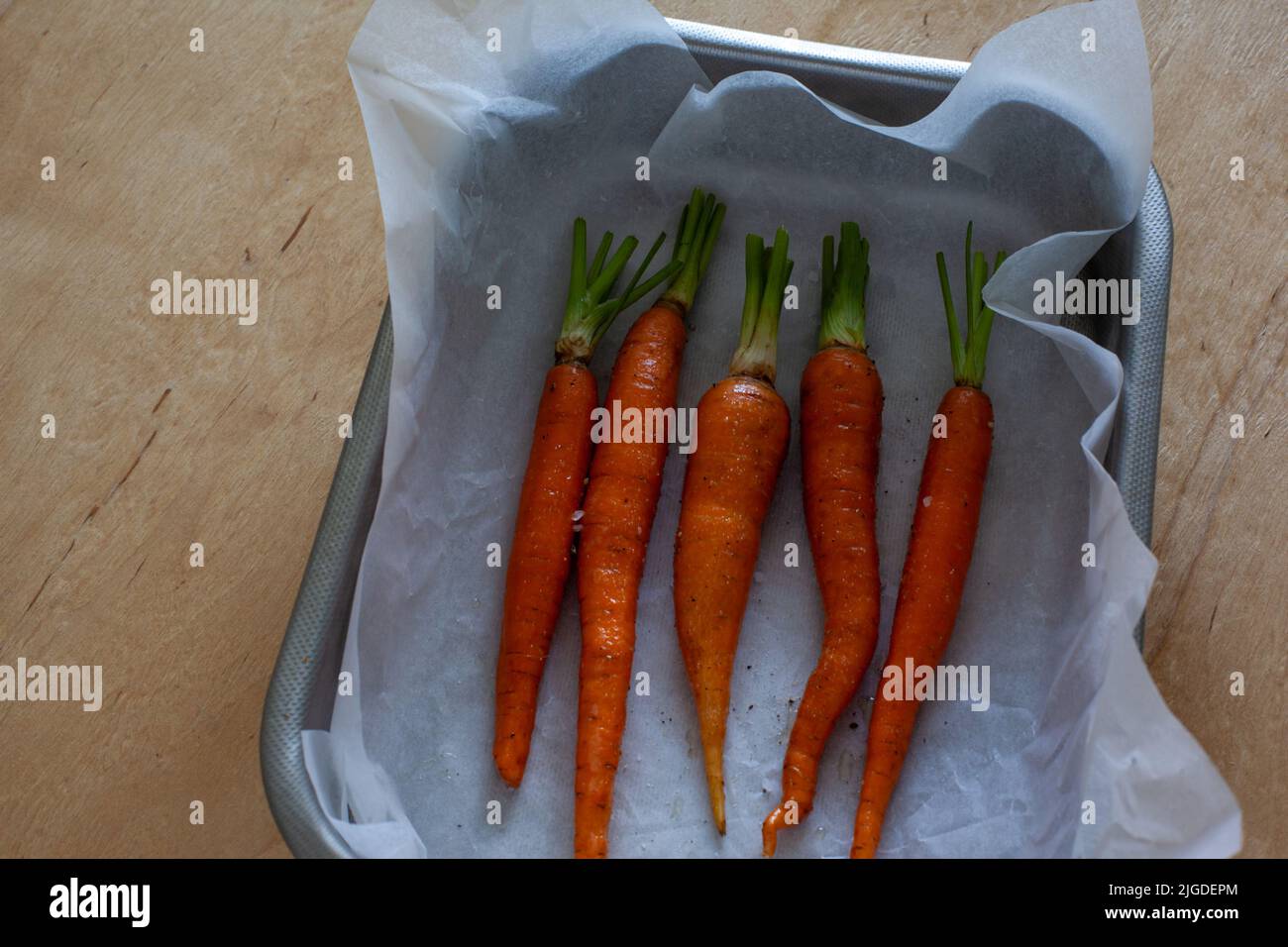 Jeunes carottes entières avec des légumes verts sur plaque de cuisson Banque D'Images