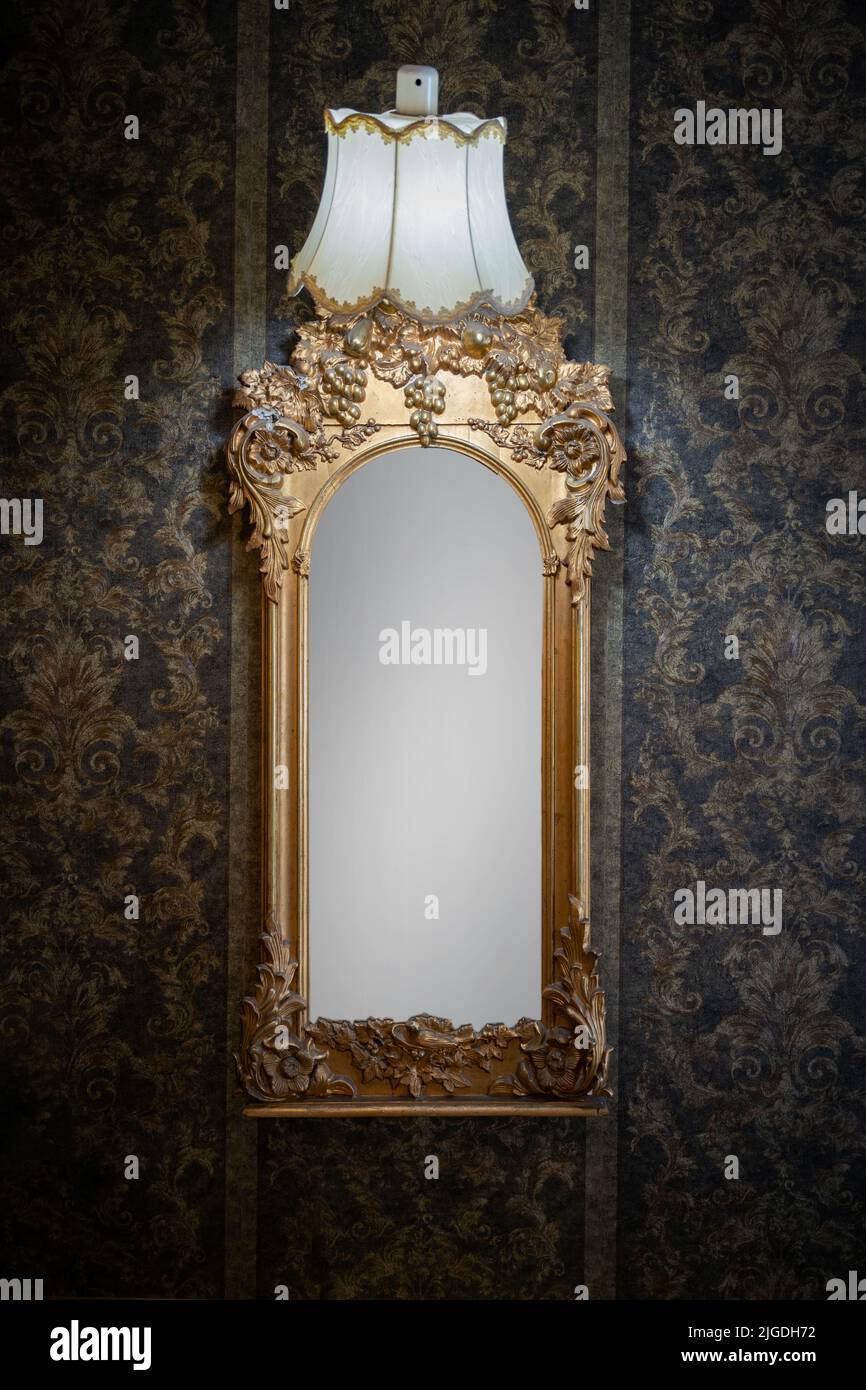 Photo verticale d'un vieux miroir vintage accroché au mur à motifs noirs Banque D'Images