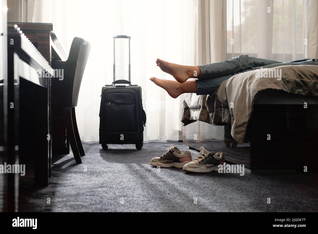 femme prenant des chaussures dans une chambre d'hôtel sur le lit. Touriste se détendre dans la chambre d'hôtel après avoir voyagé avec une valise. Femme ayant le repos après longtemps Banque D'Images