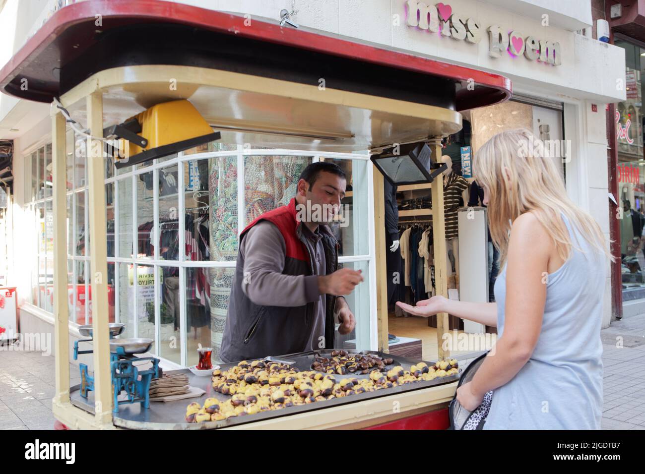 Femme achetant des châtaignes grillées à la vente de nourriture de rue dans le centre d'Istanbul, Turquie Banque D'Images